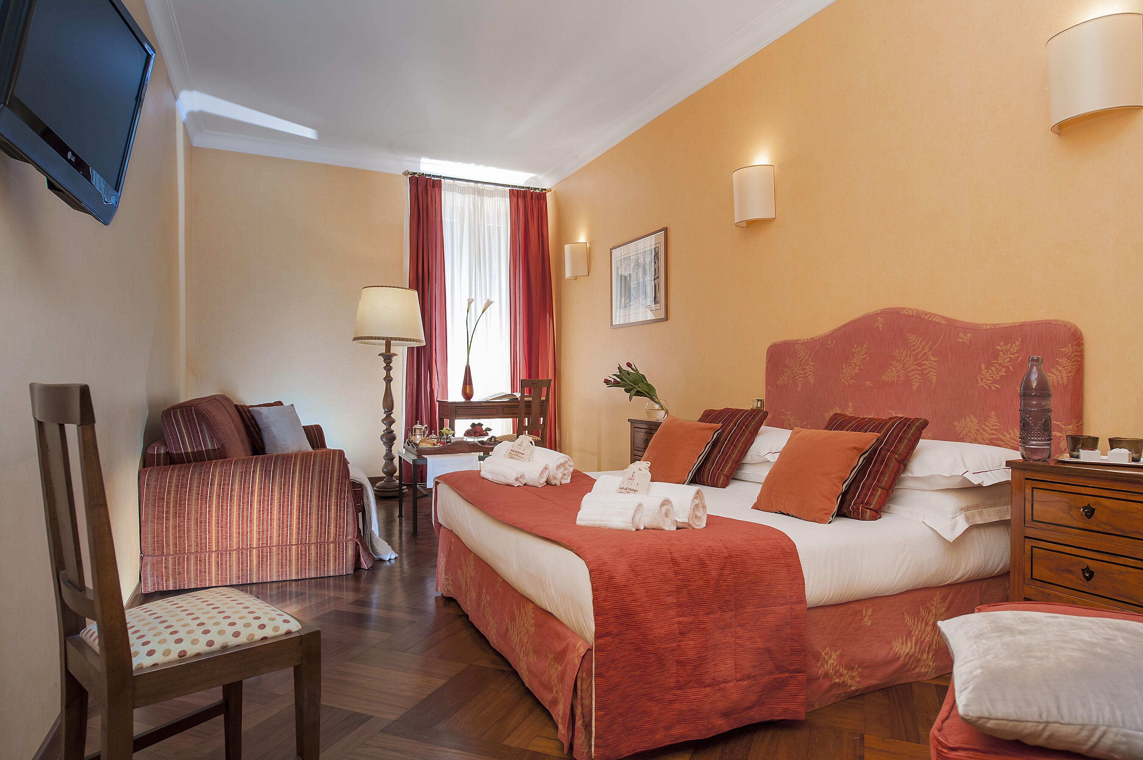A hotel room with a large bed, a desk, a chair, and a television.