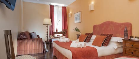 Een hotelkamer met een groot bed, een bureau, een stoel en een televisie.