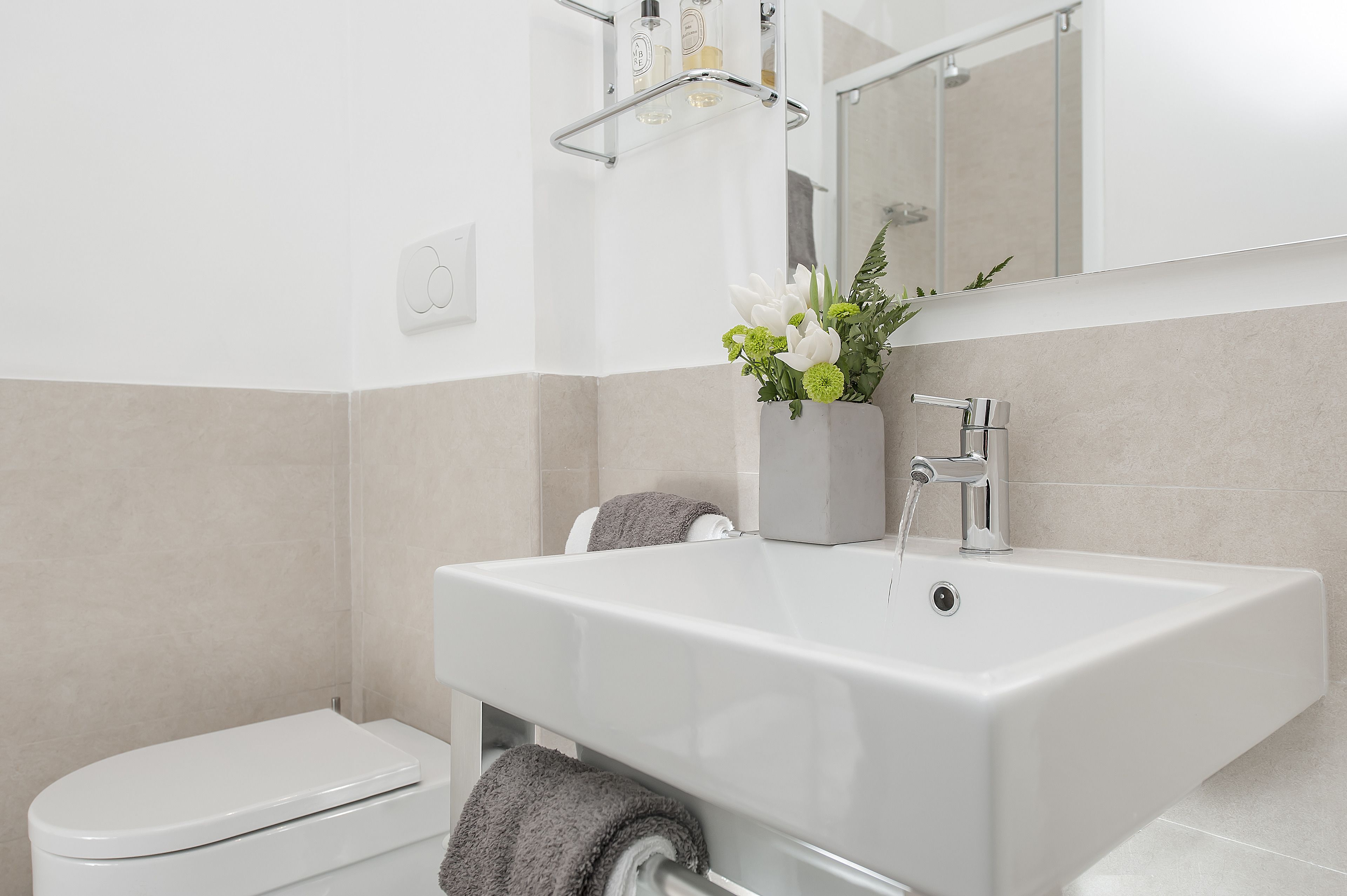Un baño moderno con un lavabo blanco, un espejo y un inodoro.