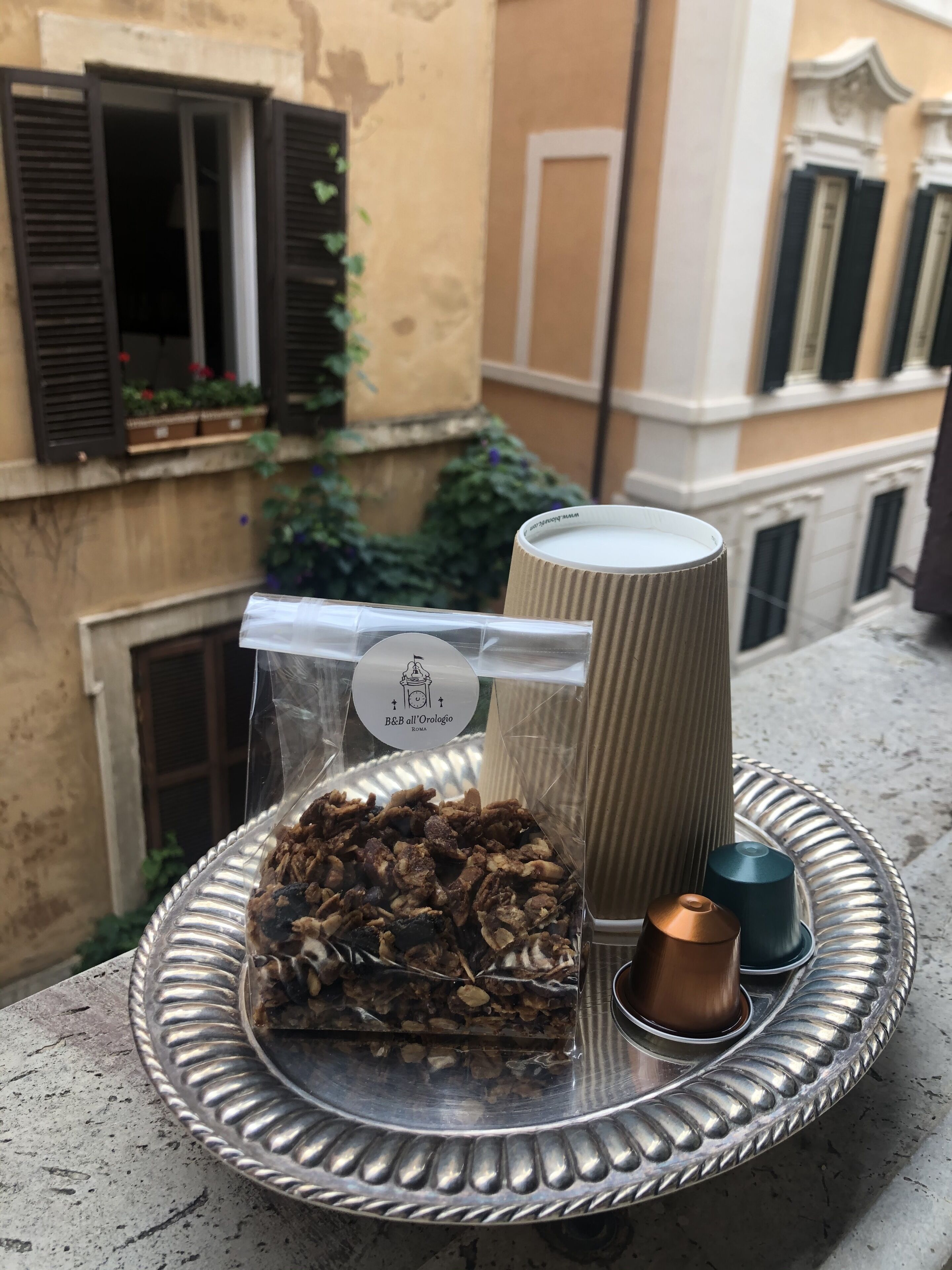 A tray with a bag of snacks, a candle, and a container of milk on a balcony.