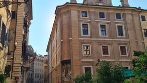 Eine Kopfsteinpflasterstraße mit historischen Gebäuden, einem Glockenturm und einer Person, die unterwegs ist.