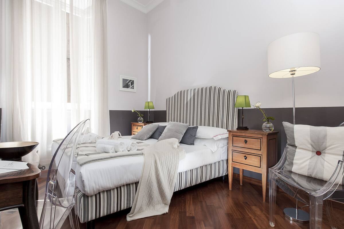 Una habitación de hotel moderna con cama, mesitas de noche, escritorio y silla.