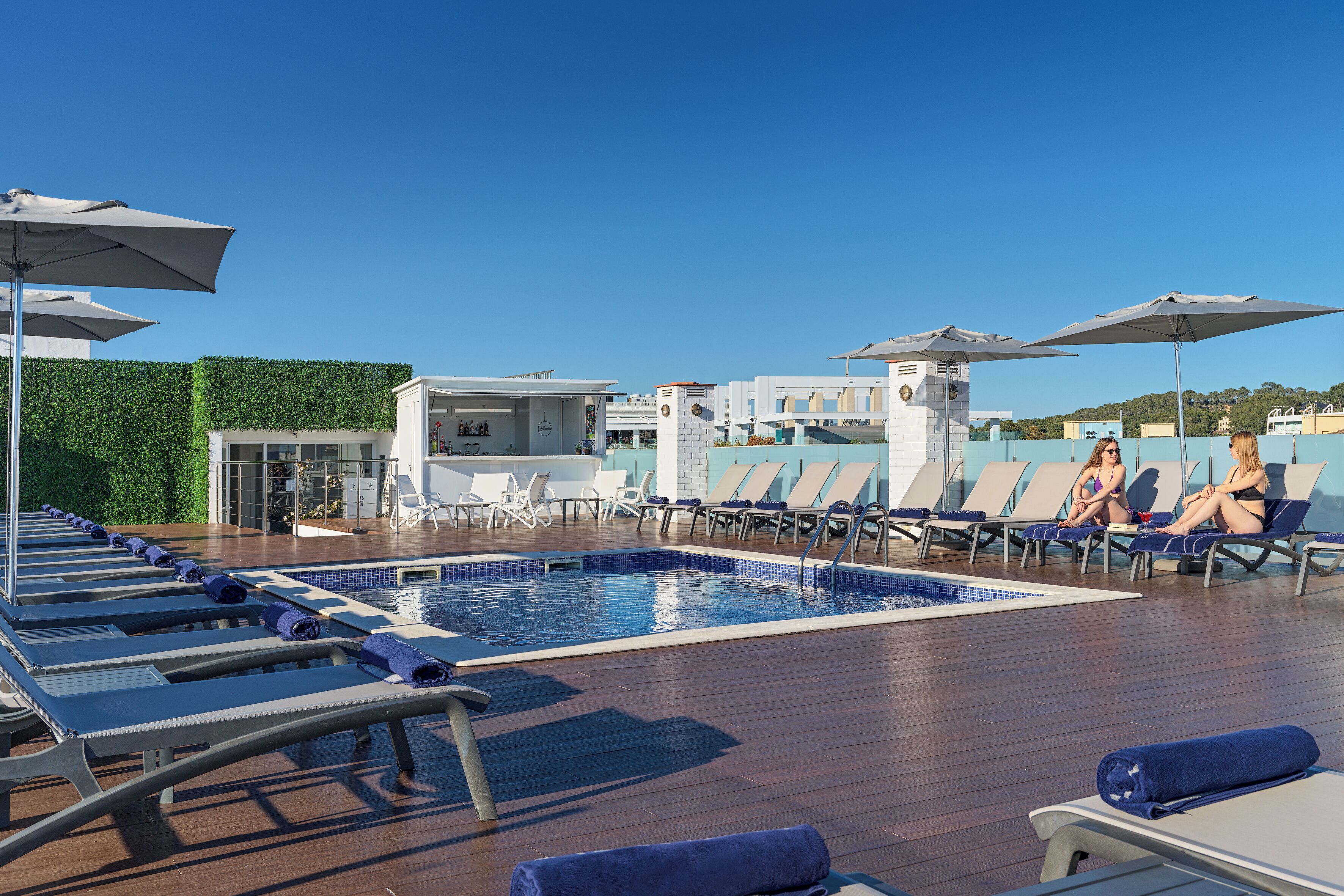 A poolside area with sun loungers, umbrellas, and a small pool.