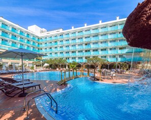 Un hotel con piscina, tumbonas y una cascada.