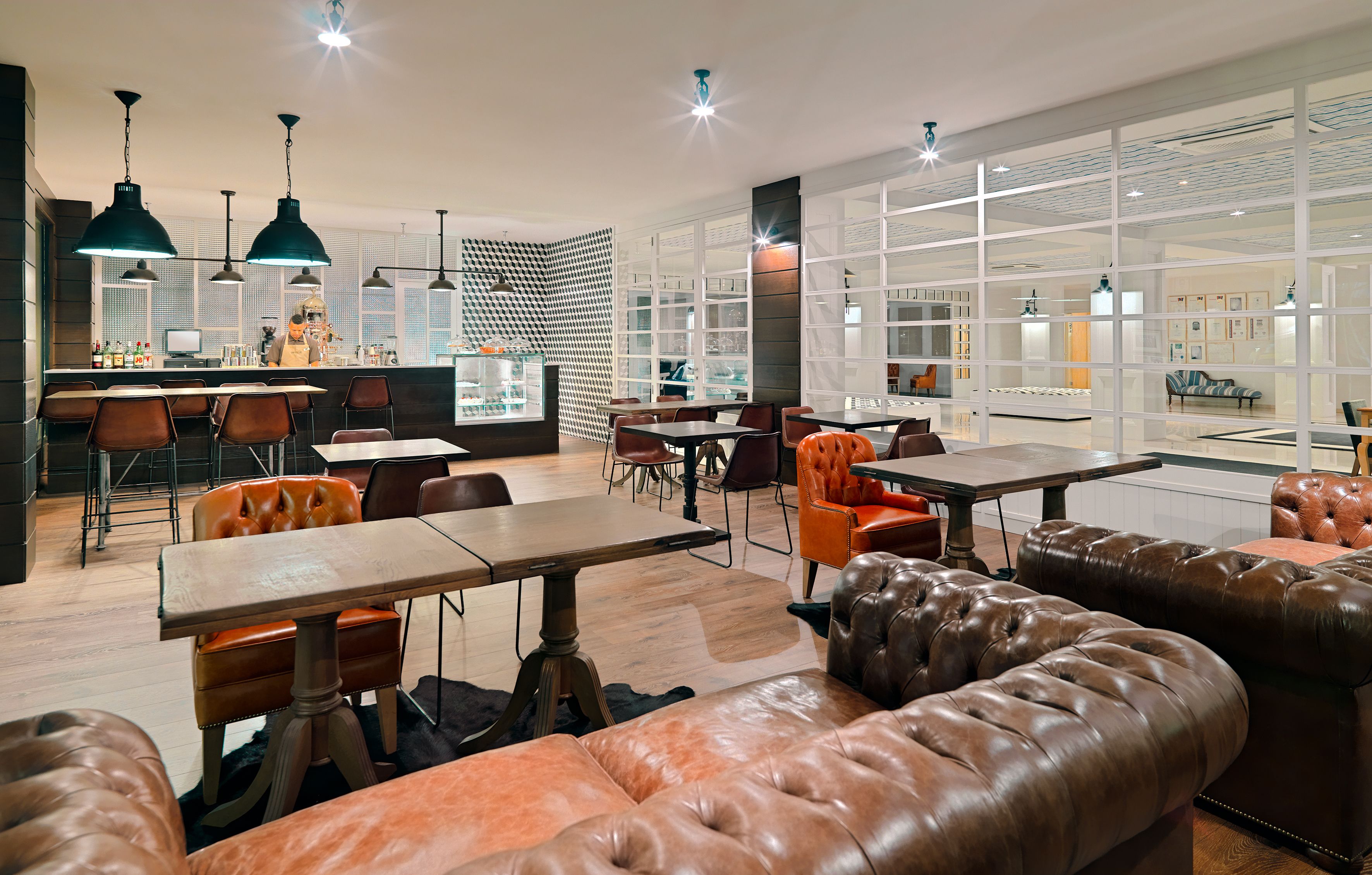Un restaurante moderno con asientos de cuero, una zona de bar y ventanas amplias.