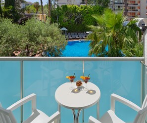 A poolside view with a table, two drinks, and lounge chairs. - H10 Delfín - Adults Only (Salou)