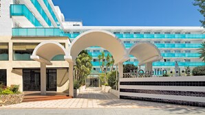A hotel with a modern design, featuring a central courtyard with arches, a pool area, and a large building with blue and white color scheme in the background. - H10 Delfín - Adults Only (Salou)