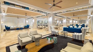 A spacious lobby with a high ceiling, multiple seating areas, and a central bar. - H10 Delfín - Adults Only (Salou)