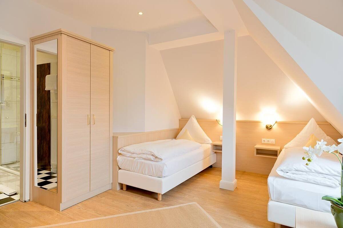 A bedroom with a bed, a wardrobe, and a nightstand with a lamp.