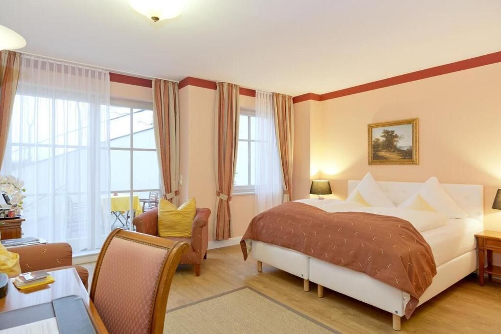 A hotel room with a bed, a desk, a chair, and a window with curtains.