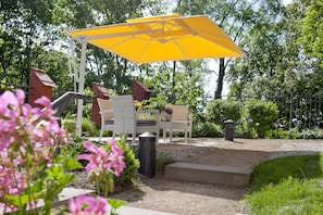 A patio with a yellow umbrella, white chairs, and a small table.