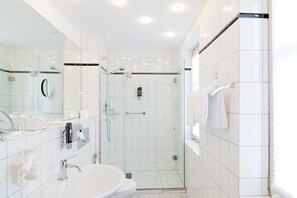 Enjoy a refreshing shower in the bathroom, featuring a glass-enclosed shower with a handheld showerhead and wall-mounted control panel.