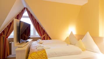 Una habitación de hotel con cama, televisión y ventana con cortinas.