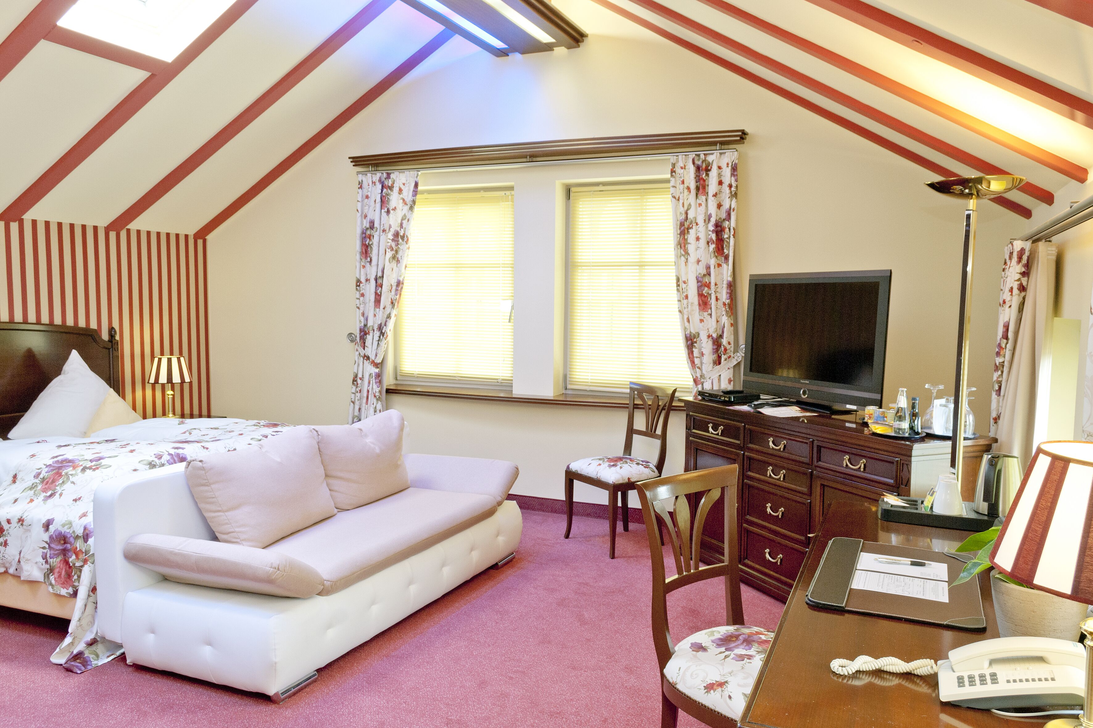 Un dormitorio con cama, sofá, escritorio con computadora, silla y televisor.
