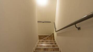 A staircase with wooden steps and white walls, leading to a landing with a light fixture.