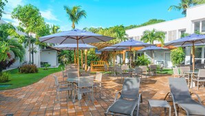 Un patio con mobiliario exterior, sombrillas y una piscina.