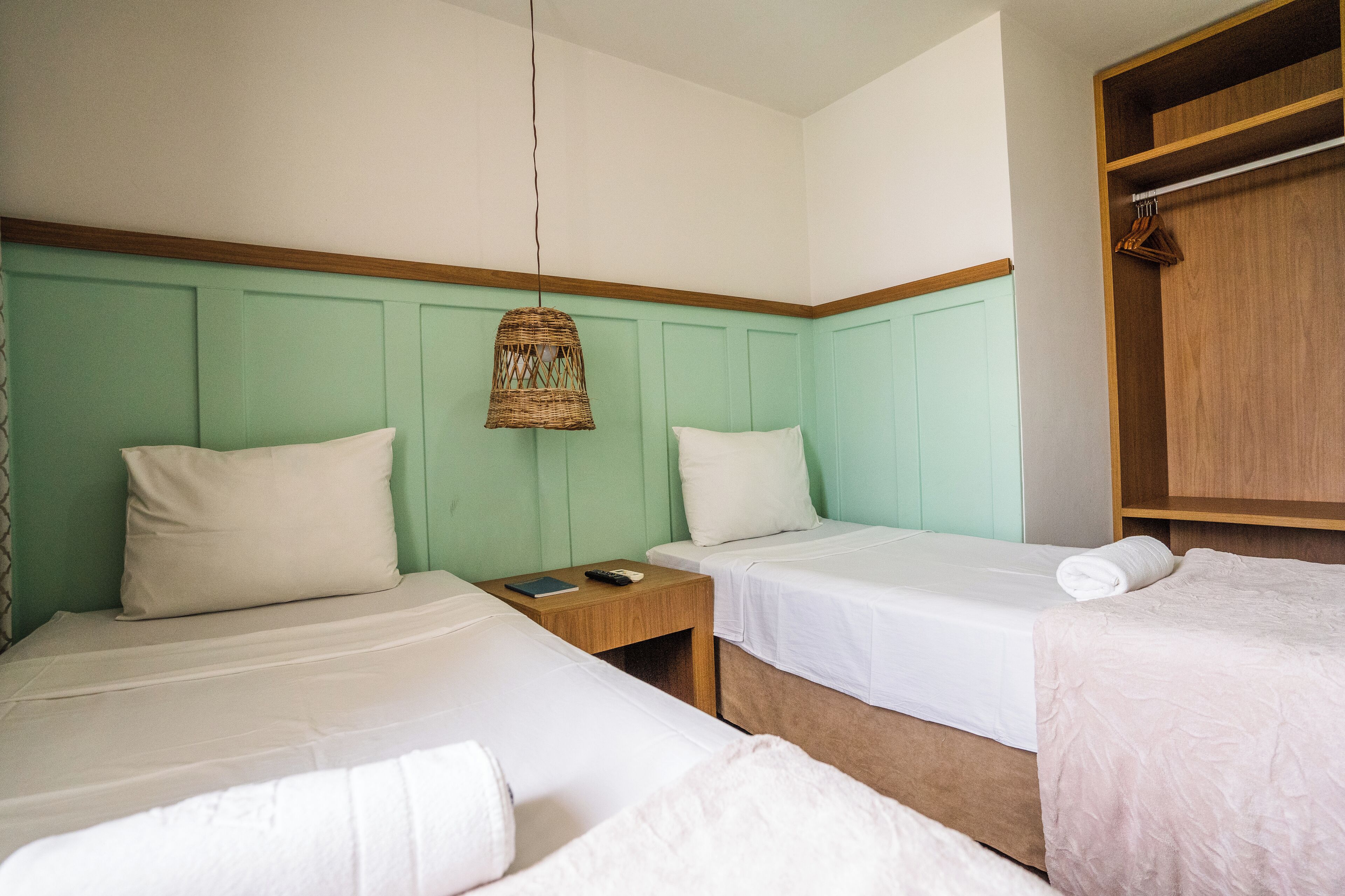Une chambre avec deux lits, une armoire en bois et un luminaire suspendu.