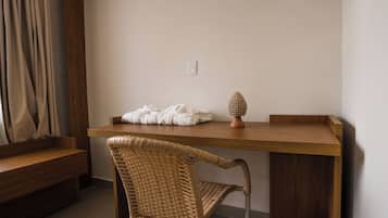 A room with a wooden desk, a wicker chair, a white towel, and a decorative object on the desk.