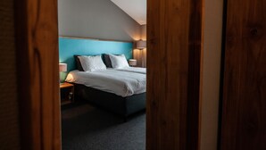 A hotel room with a bed, bedside lamps, and a wooden door frame. - Linge Hotel Elst (Elst)