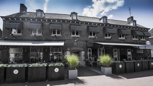 A two-story building with a dark brick facade, multiple windows, and awnings. - Linge Hotel Elst (Elst)