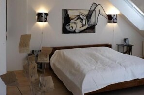 Ein Schlafzimmer mit einem Bett, zwei Wandleuchten, einem Gemälde und einem kleinen Tisch.