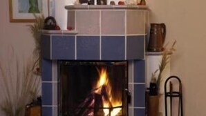 A fireplace with a tiled surround, a mantel with various items, and a framed picture on the wall.