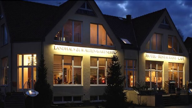 A building with a sign reading "Landhaus Zur Alten Gärtnern" and another sign for "Hotel, Restaurant, Café".