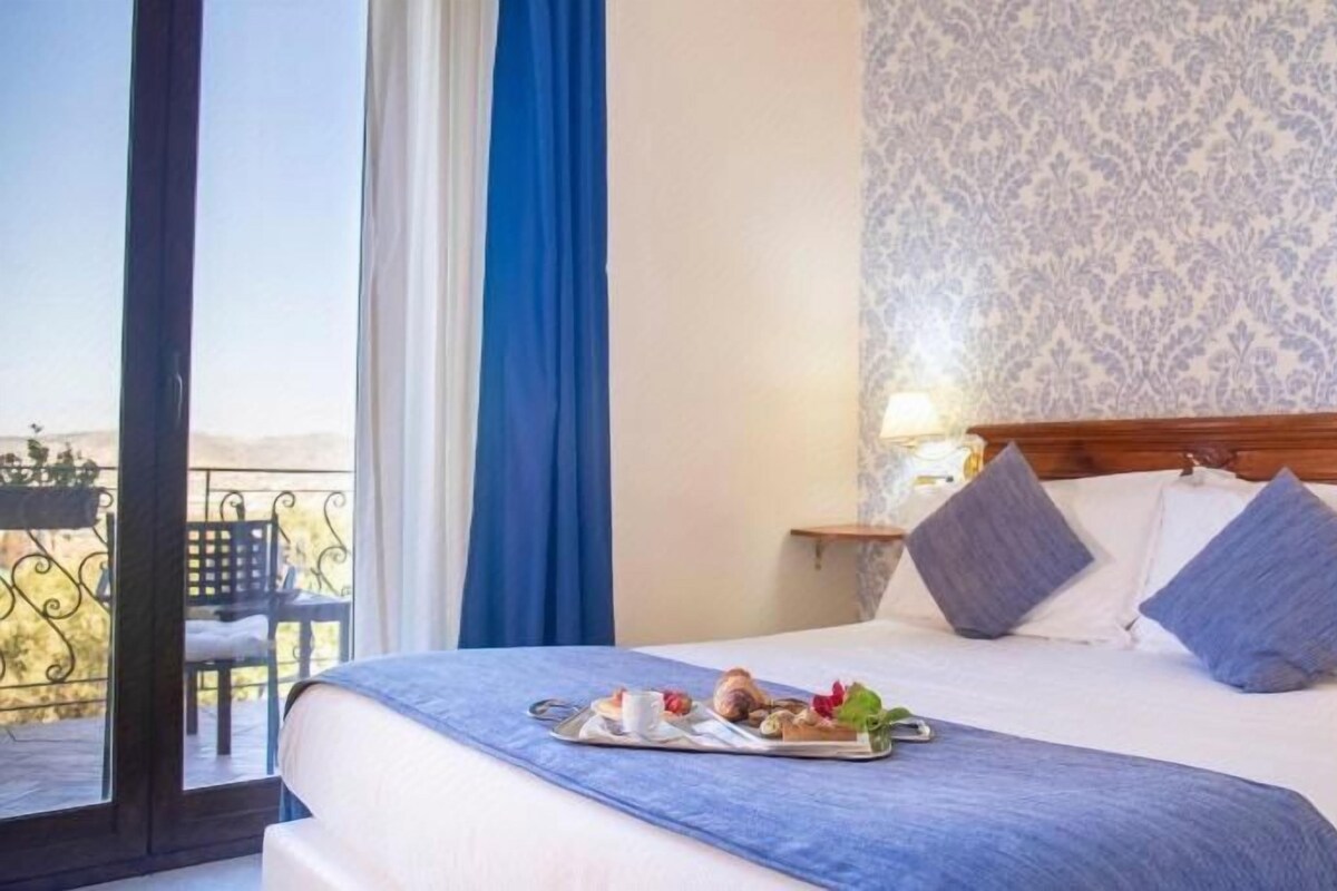 A hotel room with a bed, a balcony, and a view.