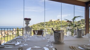 A dining table set for a meal with a view of a hill and the sea. - Villa Giuliana Relais (Licata)
