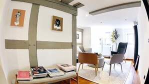 A modern living room with a wooden bench, two chairs, and artwork on the walls. - Hotel Elch (Nuremberg)