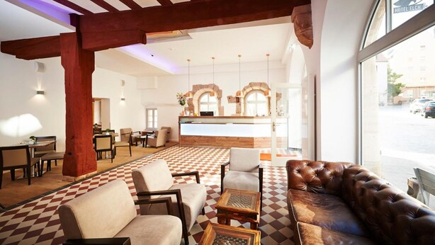 A hotel lobby with a checkered floor, leather sofas, and a reception desk with arched windows. - Hotel Elch (Nuremberg)