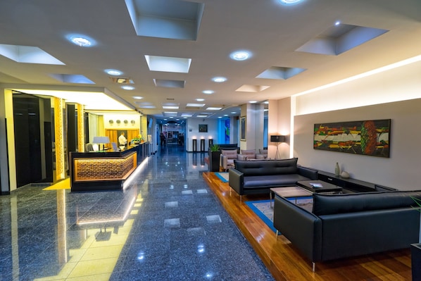 A hotel lobby with a reception desk, seating area, and a long corridor. - Radon Plaza (Sarajevo)