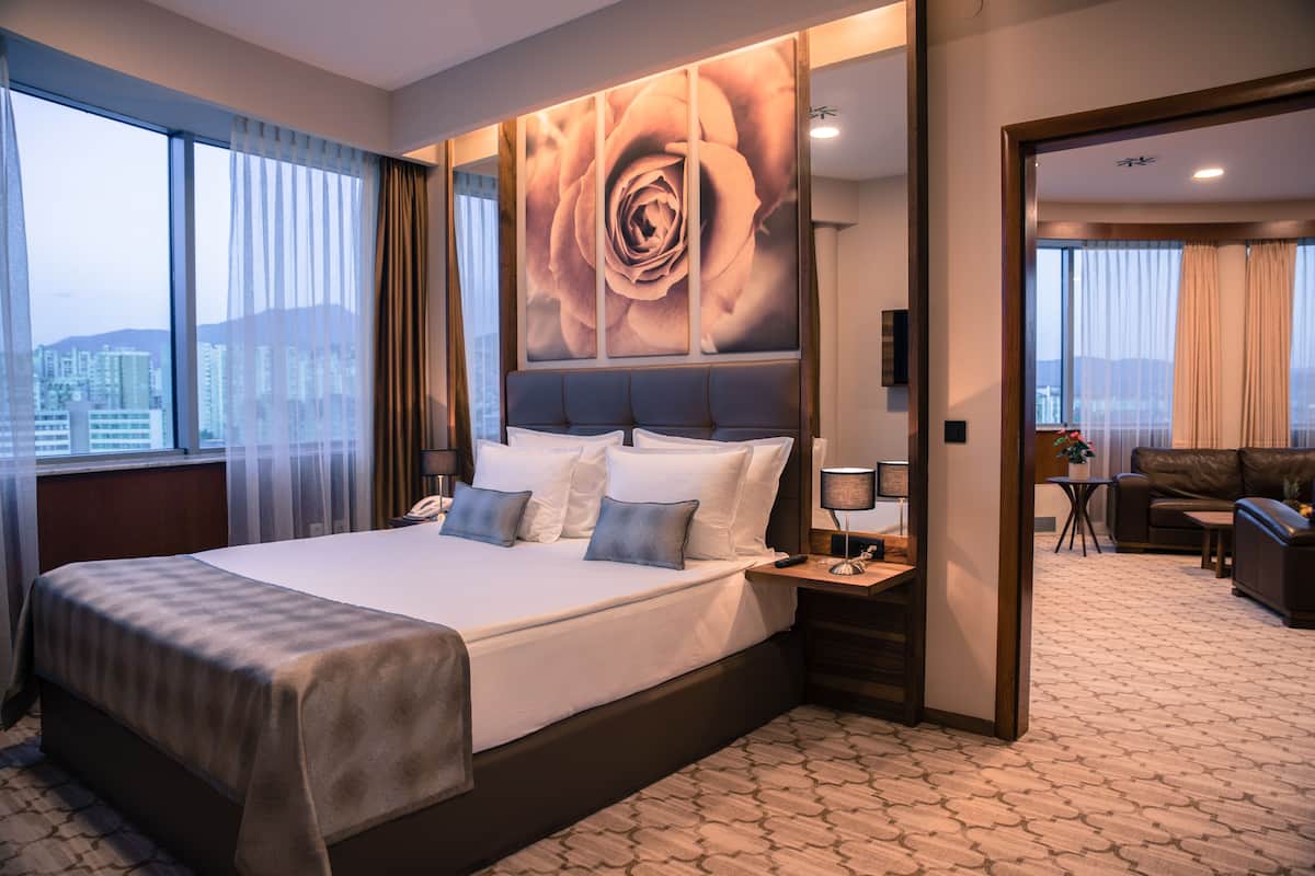Habitación de hotel con una cama grande, vista a la ciudad y un comedor.