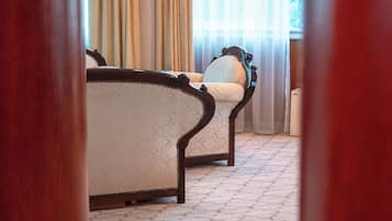 A hotel room with a bed, a chair, and a large window with curtains.