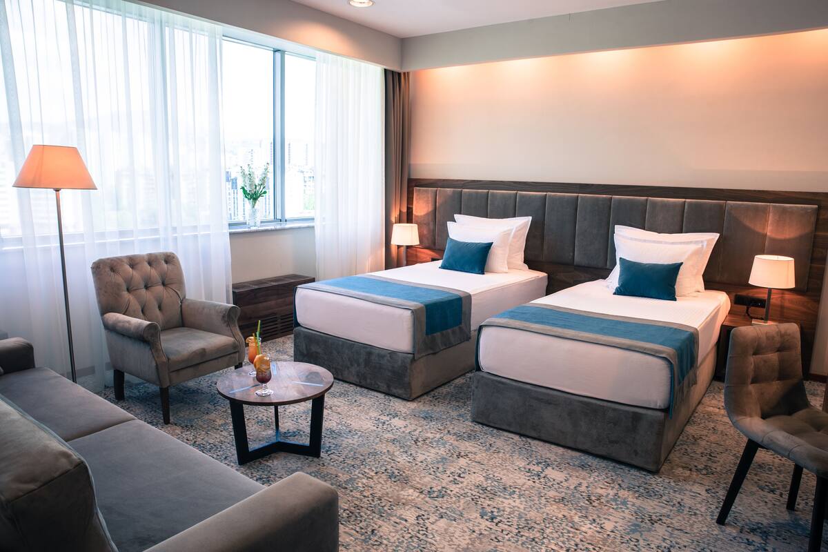 Habitación de hotel con dos camas, un sofá, una silla y una mesita.
