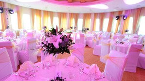 A banquet hall with round tables, white chairs, and floral centerpieces. - Radon Plaza (Sarajevo)
