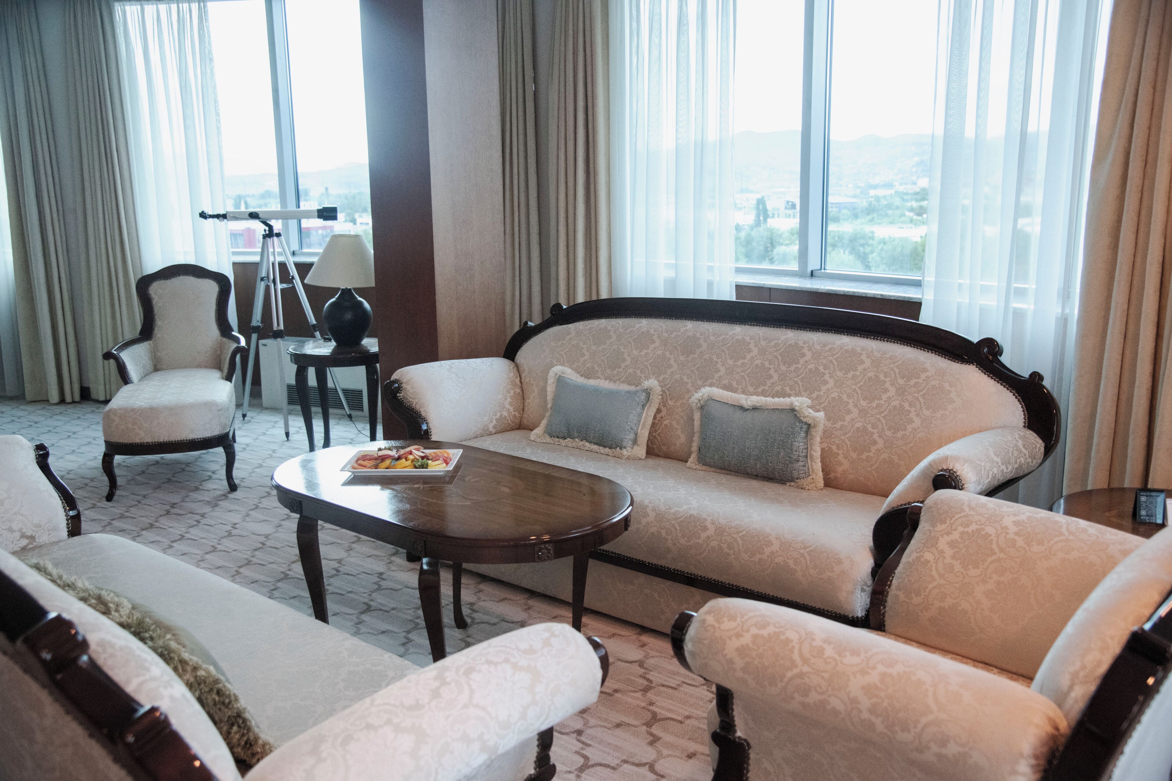A living room with a sofa, armchairs, a coffee table, and a telescope.