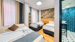 A hotel room with two beds, a wooden headboard, a large window with curtains, a wall with a colorful abstract painting, and a bathroom with blue tiles. - Fors Hotel Sultanahmet (Istanbul)