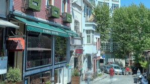 A hotel with a red facade, green awnings, and multiple windows with outdoor plants. - Fors Hotel Sultanahmet (Istanbul)