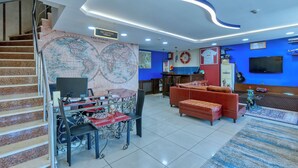 A reception area with a desk, chairs, a map, a sofa, and a TV. - Fors Hotel Sultanahmet (Istanbul)