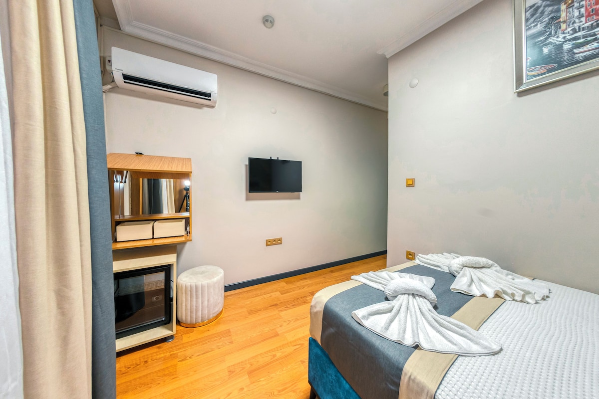 Habitació d'hotel amb un llit, televisió de pantalla plana, barra minibar i aire condicionat.