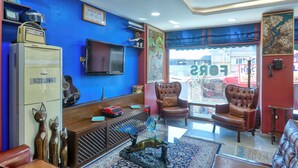 A living room with a blue wall, a television, a sofa, a chair, and a cabinet. - Fors Hotel Sultanahmet (Istanbul)