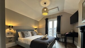 Ein Schlafzimmer mit einem Bett, Nachttischlampen, einem Schreibtisch, einem Stuhl und einem Fernseher.