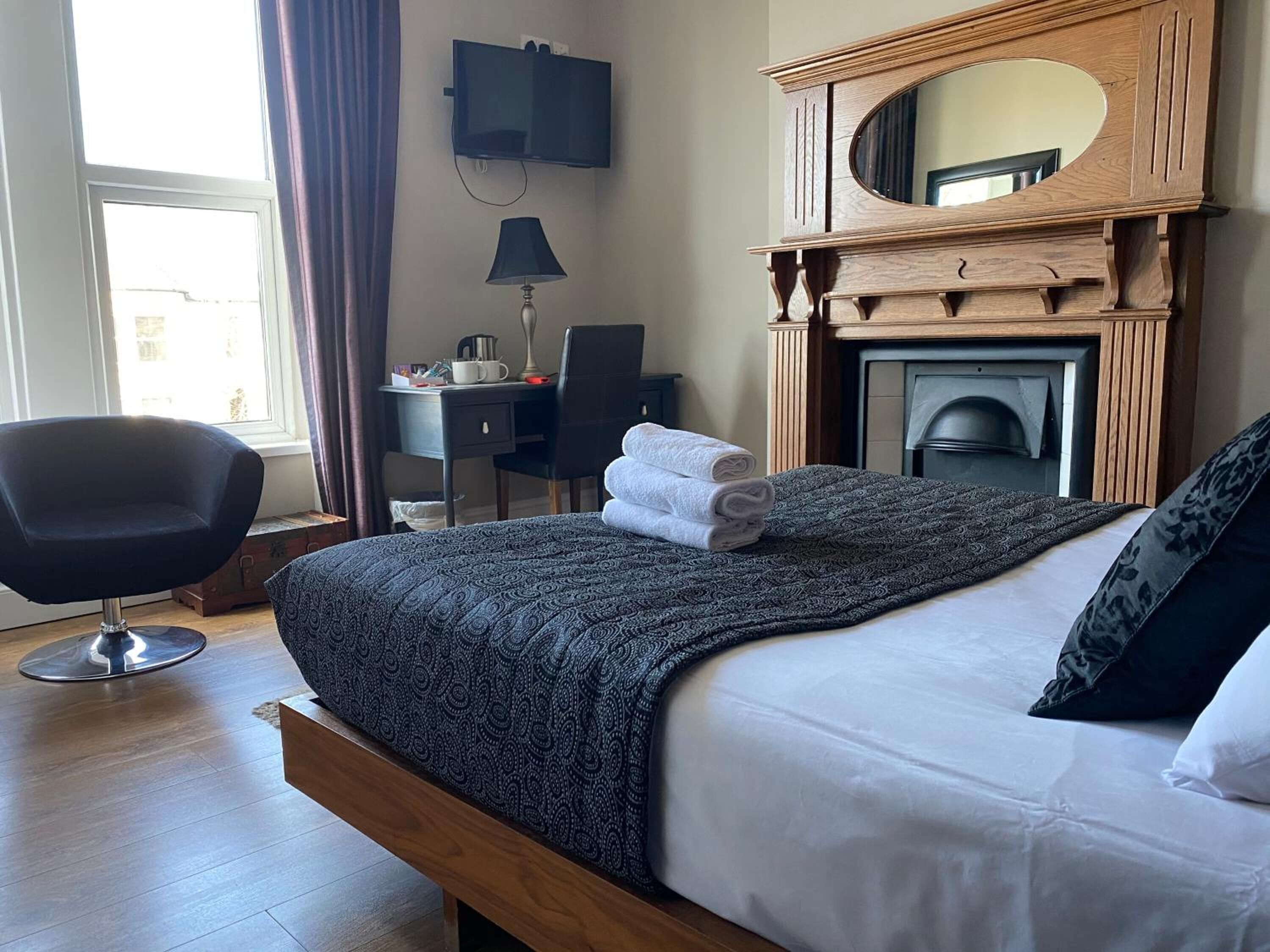Une chambre d’hôtel équipée d’un lit, d’un bureau, d’une chaise, d’une télévision et d’une cheminée.
