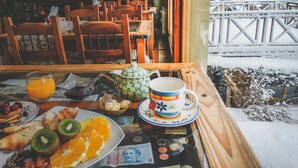 A breakfast table with fruit, pastries, and a teapot.