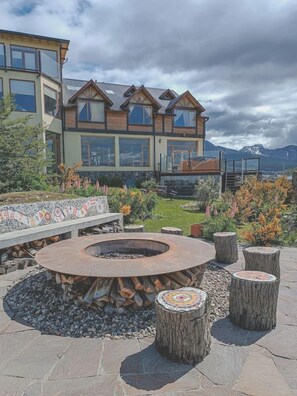A circular fire pit with logs, surrounded by stone seating and a stone pathway.