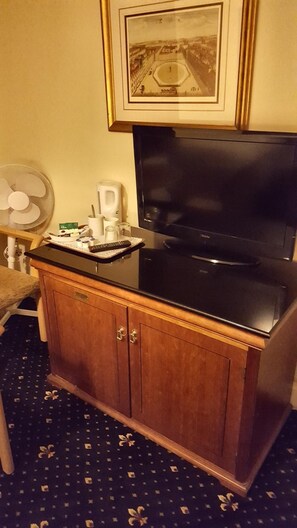 A kitchenette with a black stove, a white coffee maker, and a remote control on the counter. - New Oscar (Windsor)