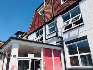 A two-story building with a red-tiled roof, white brick walls, and multiple windows. - New Oscar (Windsor)