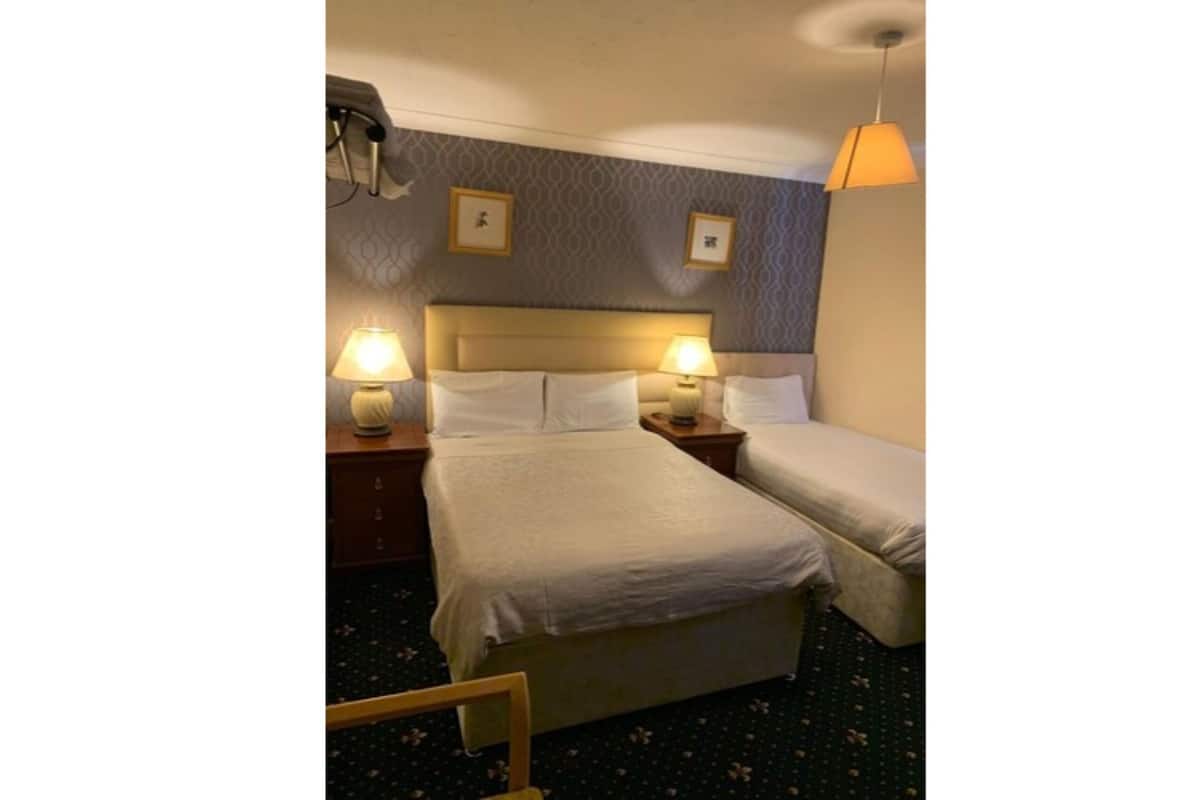 Ein Hotelzimmer mit zwei Betten, einem Kopfteil, Nachttischlampen und einem Deckenventilator.