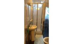A bathroom with a glass shower enclosure, a sink, and a toilet. - New Oscar (Windsor)